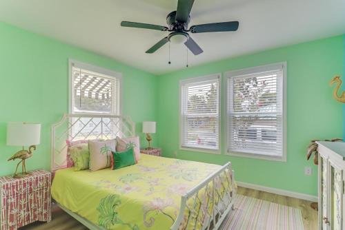 a bedroom with a bed with green walls and a ceiling fan at The Tropical Cottage in Long Beach