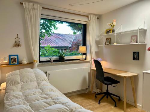 a bedroom with a bed and a desk and a window at Cheerful house, close to lakes in Farum