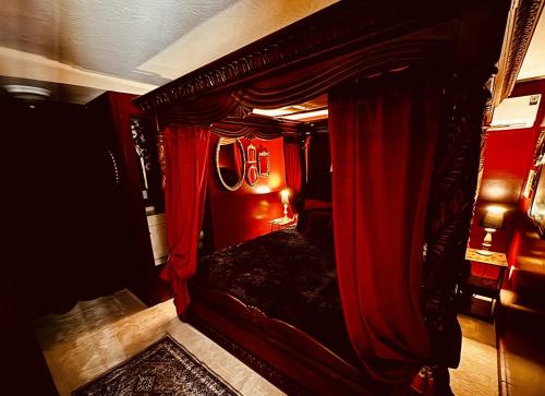 a bedroom with a canopy bed with red curtains at Sunset in Hillsboro