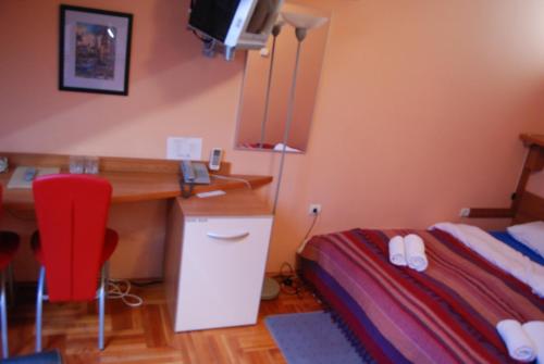 a bedroom with a desk and a bed with a red chair at Car Royal Apartments and Rooms in Novi Sad