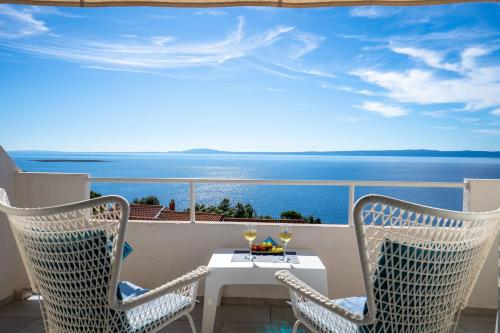 a table and chairs on a balcony with a view of the ocean at Libera Apartments in Stara Baška