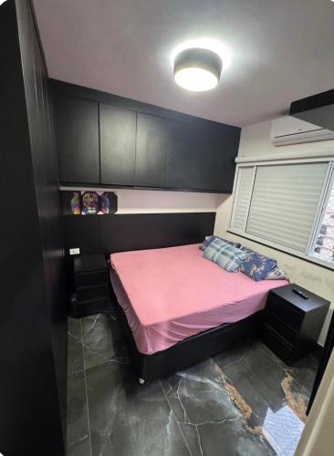 a small bedroom with a pink bed in it at AP FRENTE MAR Compacto, Completo e Confortável in São Vicente