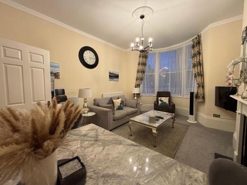 a living room with a couch and a clock on the wall at Moat Stays Victorian, Sea View! in Kent