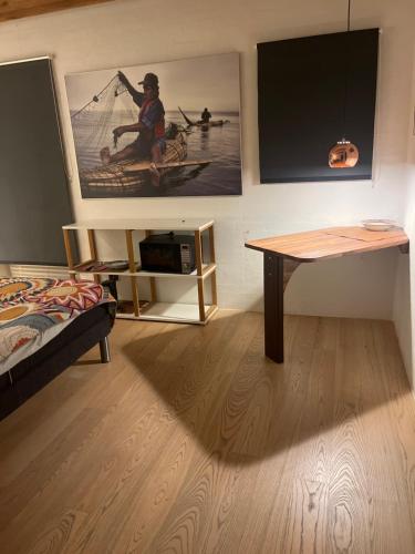 a room with a table and a picture of a man in a canoe at Stråtækt Idyl in Nørre Kollund