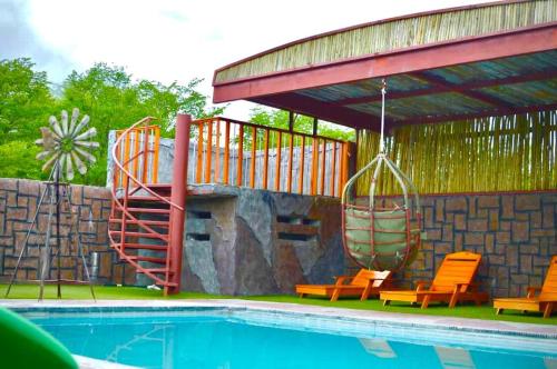 a swimming pool with orange chairs and a slide at Makgadikgadi Riverview Inn in Nata