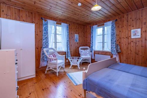 a bedroom with a bed and chairs and wooden walls at BLE876-Holmsjoe-Husgoel-216 in Holmsjö