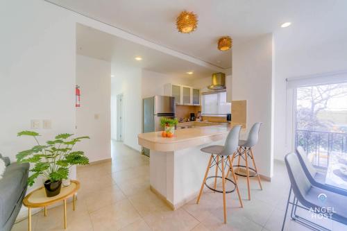 a kitchen with a counter and chairs in a room at Walk to 5th Ave & Beach - Pools, Balcony & Parking in Playa del Carmen
