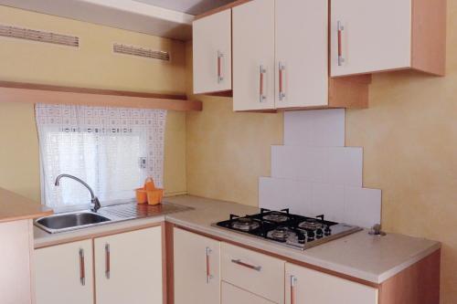 a kitchen with white cabinets and a stove and a sink at Camping Village Torre Pendente in Pisa