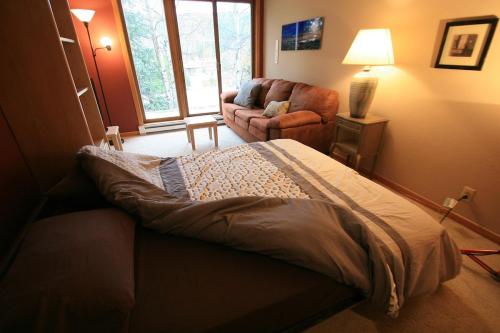 a bedroom with a bed and a living room with a couch at Mountain Adventure Basecamp + Hot Tubs in Winter Park