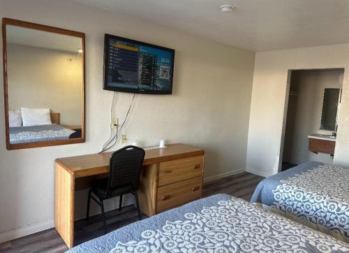 a hotel room with a desk and a mirror at Best Economy Inn & Suites in Bakersfield
