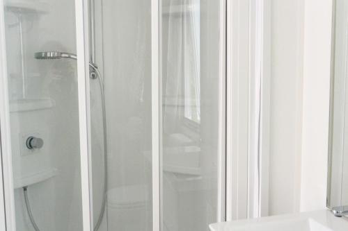 a shower with a glass door next to a toilet at Camping Village Torre Pendente in Pisa