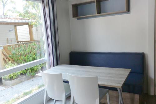 a dining room table with white chairs and a window at Camping Village Torre Pendente in Pisa