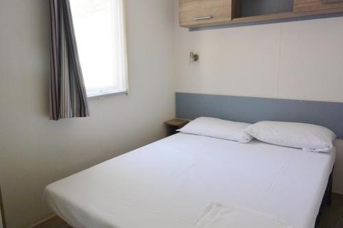 a white bed in a room with a window at Camping Village Torre Pendente in Pisa