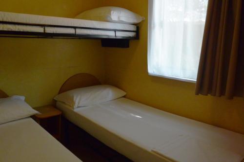 two beds in a small room with a window at Camping Village Torre Pendente in Pisa