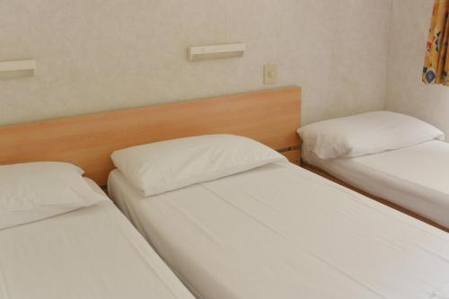 two beds in a room with white sheets at Camping Village Torre Pendente in Pisa