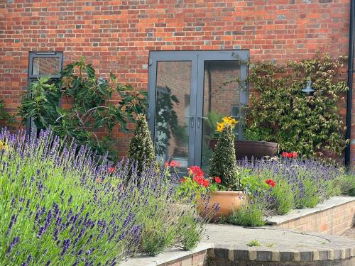 a garden with flowers in front of a brick building at Chiltern Studio in Wendover
