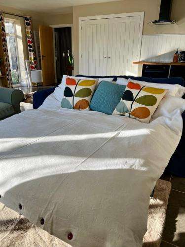 a large white bed with colorful pillows on it at Chiltern Studio in Wendover