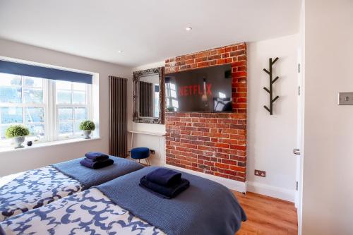 a bedroom with a large bed and a brick wall at The Simms Suite in Worthing