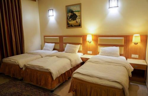 two beds in a hotel room with two lamps at Jawaher hotel in Karbala