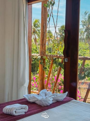 a bed with a window with a view of a garden at Pousada Vila Bella Icaraí in Icaraí