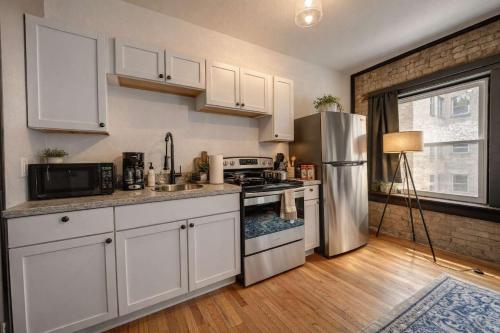a kitchen with white cabinets and a stainless steel refrigerator at Amazing Studio McKinley Beach - Brady St Lowr East in Milwaukee