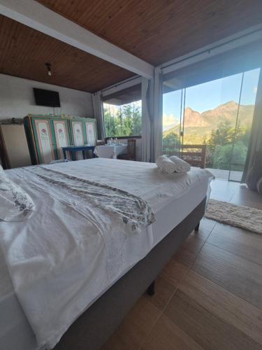a large bed in a room with a large window at Pedra Azul Chalé Clássico in Domingos Martins