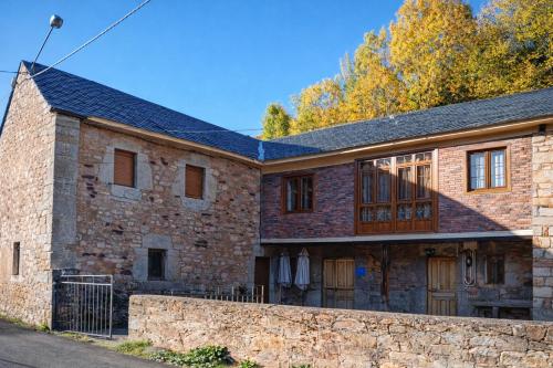 an old brick house with a stone wall at Casa La Farrapona Torrestío Babia in Torrestío
