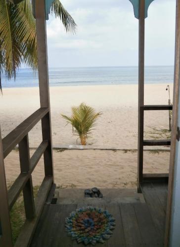 a view of the beach from the porch of a beach house at Rainbow Tioman Cottage in Kampong Juara