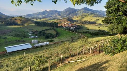a farm in a field with mountains in the background at Rancho Ca Fé - Casa Rural in Brazópolis