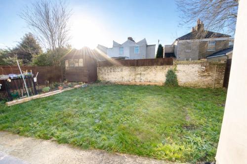 a backyard with a brick wall and a yard at Evo C - 2 Bed Apartment 2 Min Walk to Station - longer stays available in Gravesend