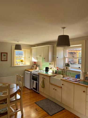 a kitchen with white cabinets and a table and a dining room at The Cottage Bailieborough Cavan in Bailieborough