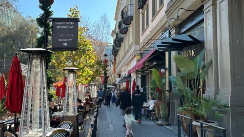a group of people walking down a street with shops at Santana Row Garden Retreat Private Executive Residence with Koi Pond and Waterfall Walk to Santana Row Valley Fair Dining and Shopping Private Entrance in San Jose