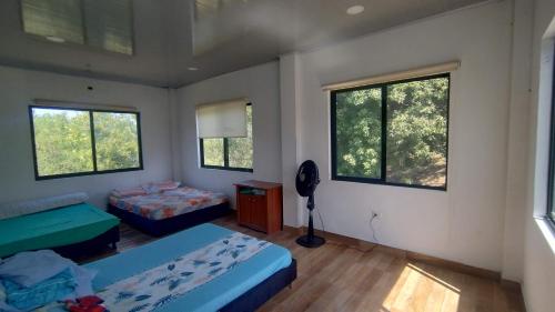 a room with two beds and two windows at Casa Nueva en Condominio in Girardot