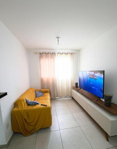 a living room with a yellow couch and a flat screen tv at Apartamento 2 Quartos com Piscina e Garagem in Maceió
