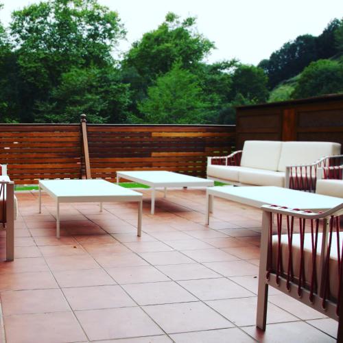 a patio with white couches and tables on a deck at Txikierdi Alde Auto Check-in in Oiartzun