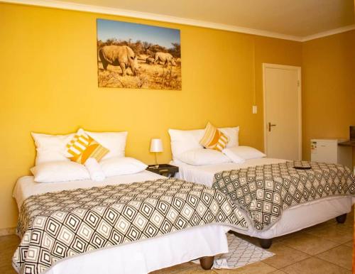 due letti in una stanza con pareti gialle di Josef Self Catering a Swakopmund