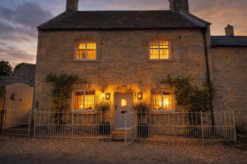 an old brick house with its lights on at Jasmine Cottage, Upper Slaughter, Cotswolds in Cheltenham