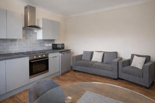 a kitchen and living room with a couch and a table at Evo C - 2 Bed Apartment 2 Min Walk to Station - longer stays available in Gravesend