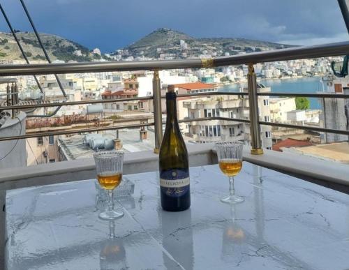 a bottle of wine and two glasses on a table at Pinkapartment Saranda in Sarandë