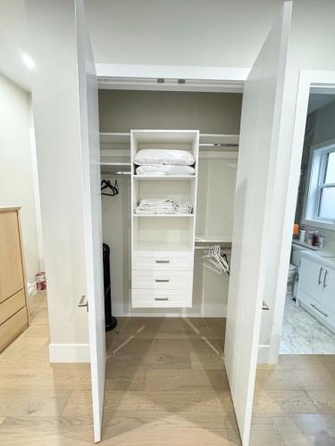 a walk in closet with white cabinets and a window at Excellent Place to Stay in Coquitlam