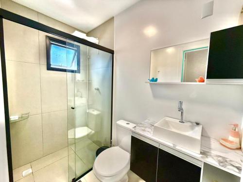 a bathroom with a shower and a toilet and a sink at Apartamento Pousada Essence Navegantes Praia Gravata in Navegantes