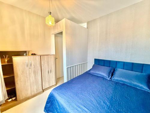 a bedroom with a blue bed and a cabinet at Apartamento Pousada Essence Navegantes Praia Gravata in Navegantes