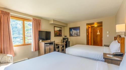 a hotel room with two beds and a flat screen tv at Cahilty #265 in Sun Peaks