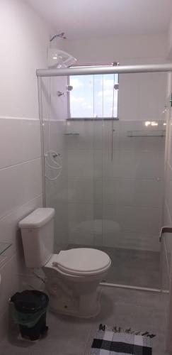 a bathroom with a toilet and a glass shower at Apartamento Studio in Barbacena