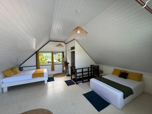 a attic bedroom with two beds and a window at Ave Surfing House in Mahina