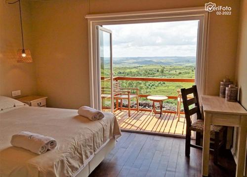 a bedroom with a bed and a balcony with a view at El Abrazo de las Sierras in Minas