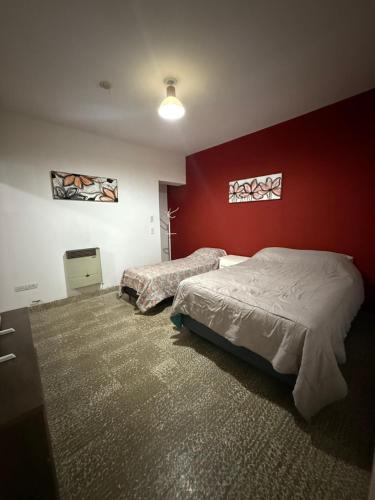 a bedroom with two beds and a red wall at HOSTEL del MUNDO in Villa María