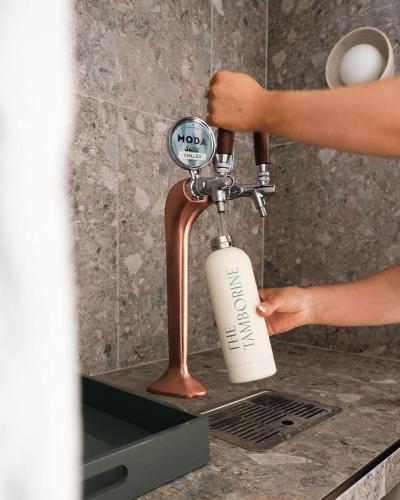 a person holding a soap bottle under a faucet at The Tamborine - Boutique Hotel in Mount Tamborine