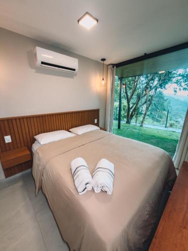a bedroom with a large bed with towels on it at Chale Container no Centro de Petrópolis in Petrópolis
