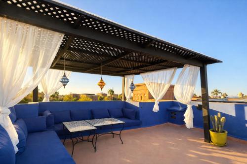 a patio with a blue couch and white curtains at Private Riad Alemania in Marrakesh - Pool - Rooftop in Marrakesh